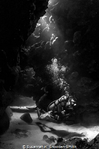 Light filters onto a diver as he emerges from a swim through by Susannah H. Snowden-Smith 